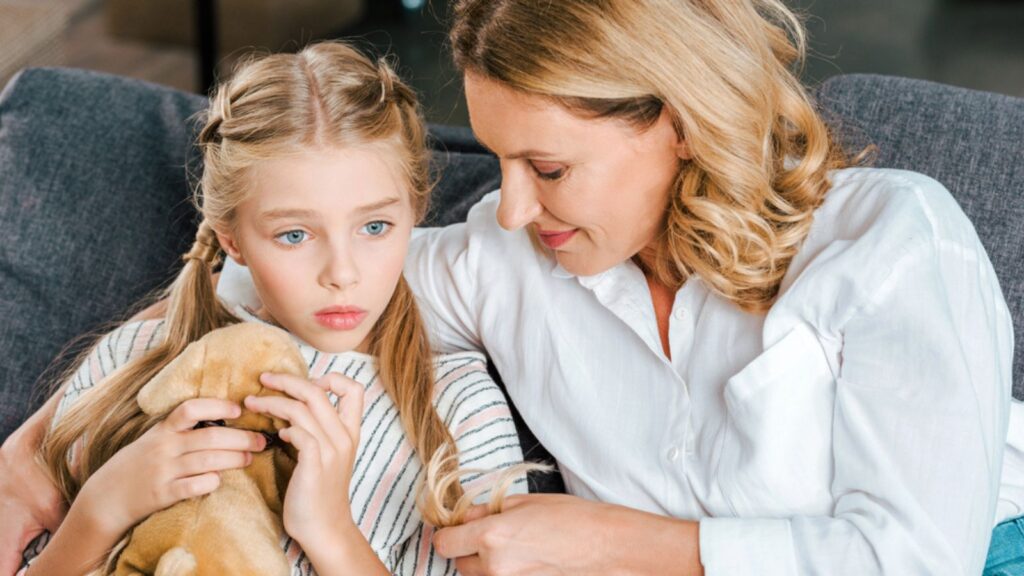 High angle view of mother and daughter sitting on couch together and chatting