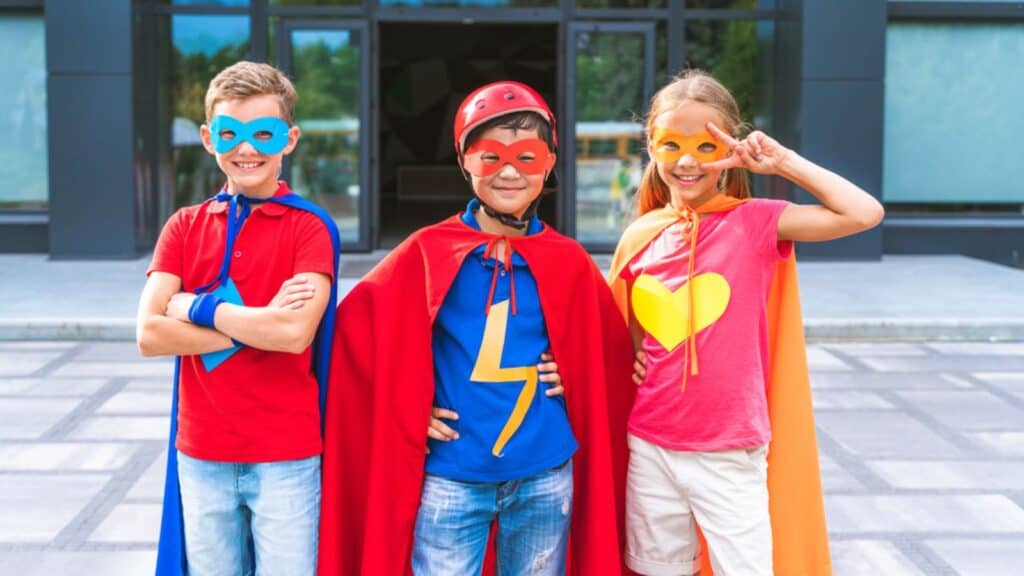 Kids smiling and wearing superhero costumes