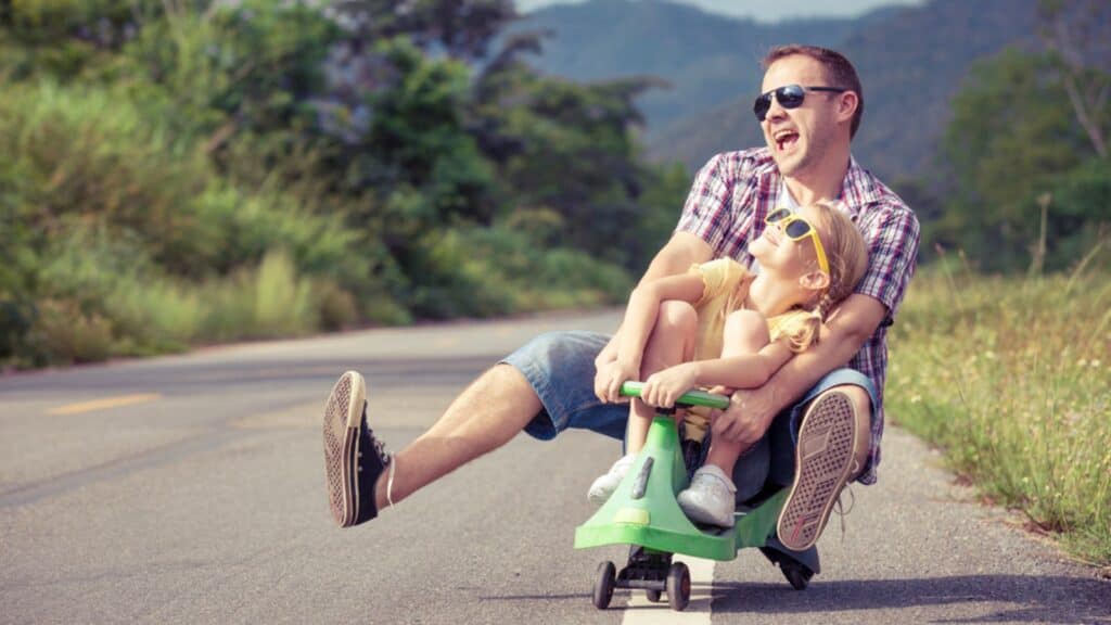 Laughing dad and daughter playing on the road