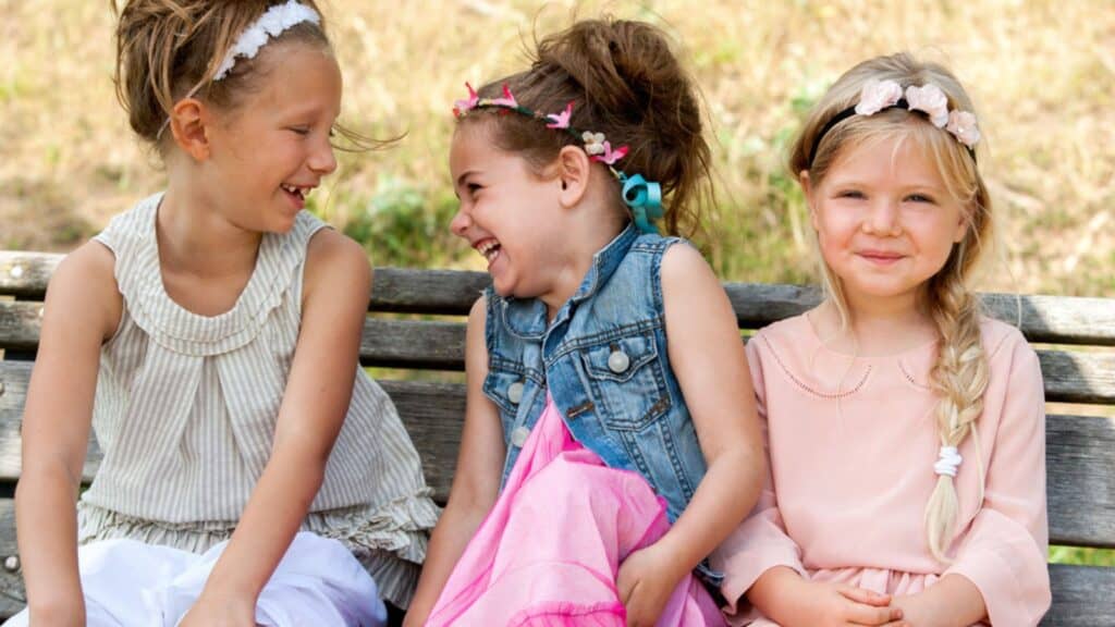 Laughing kids sitting on wooden bench
