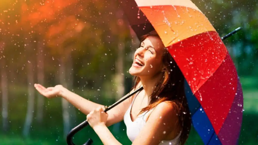 Laughing woman with umbrella checking for rain