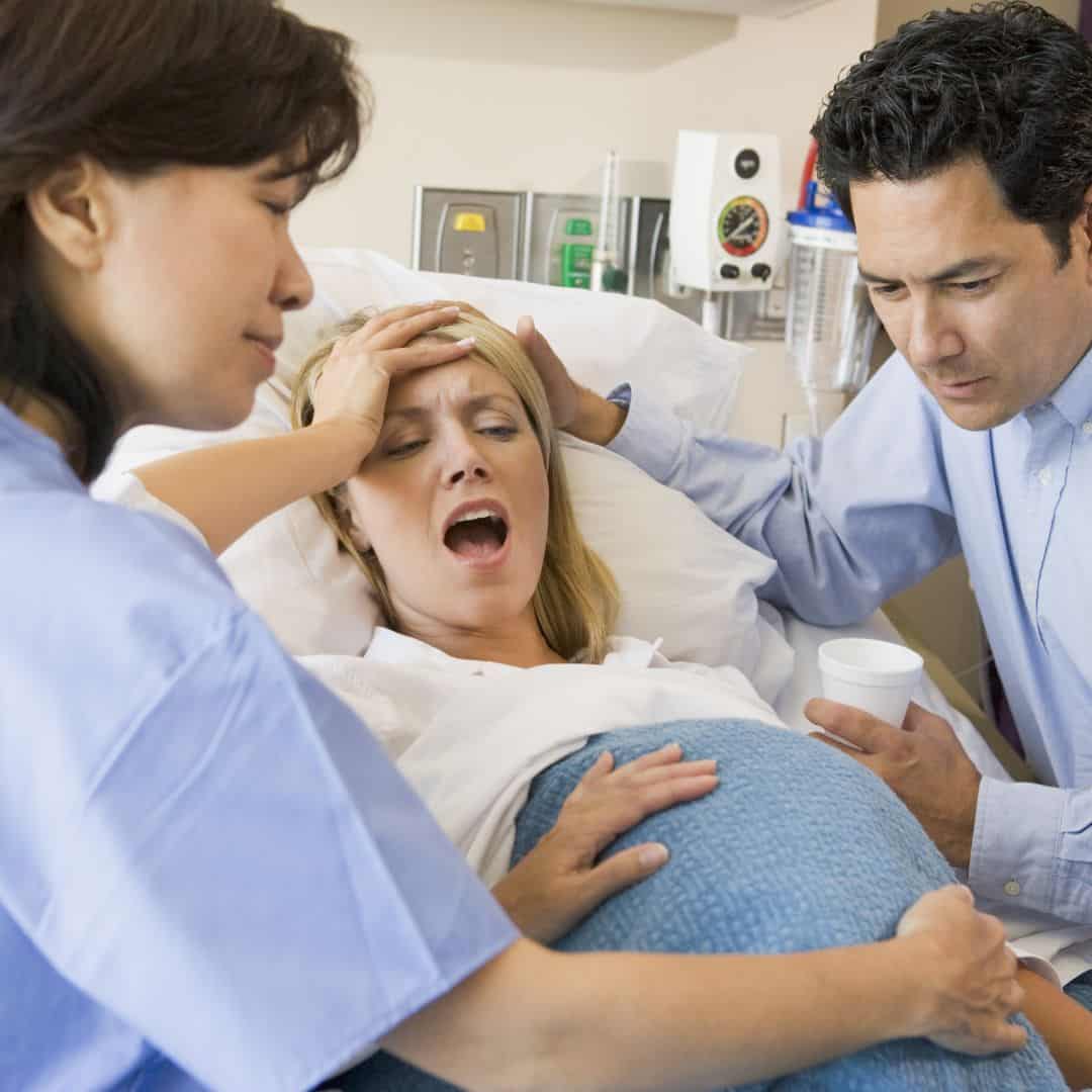 Woman in labor with a nurse and a doctor comforting her