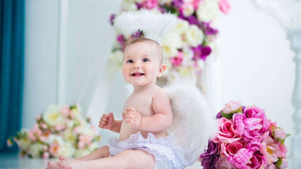 Little angel baby girl smiling and happy sitting on the background of flowers and harp