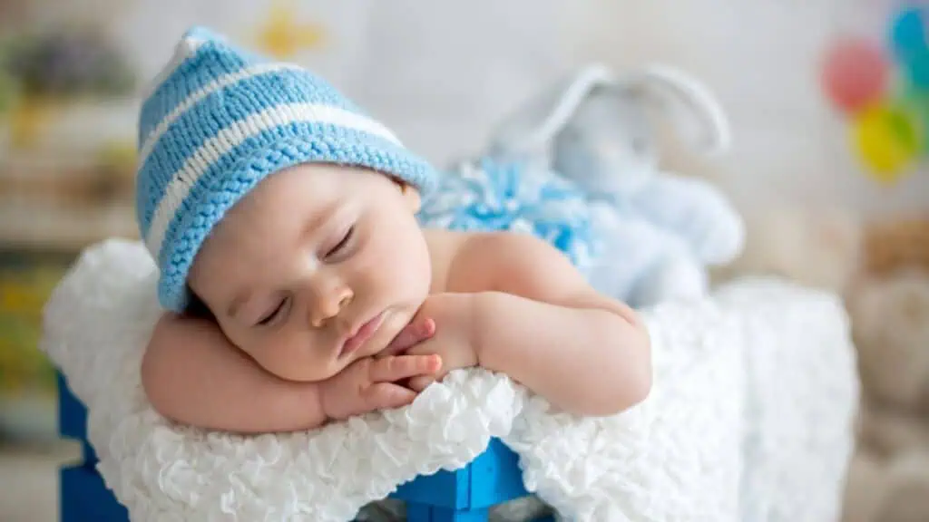 Little baby boy with knitted hat, sleeping with cute teddy bear