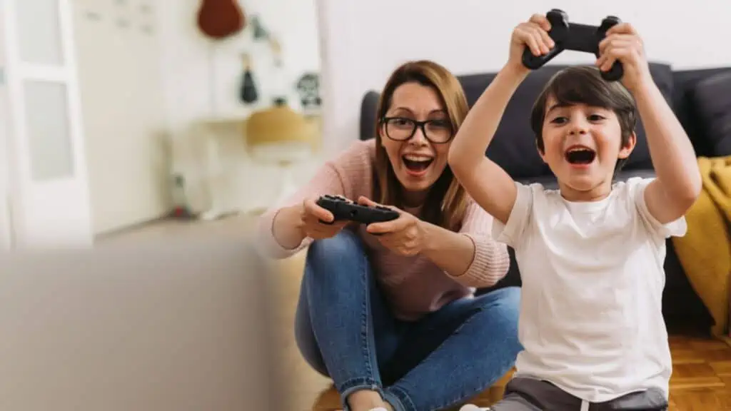 Little boy playing video games with his mom at home