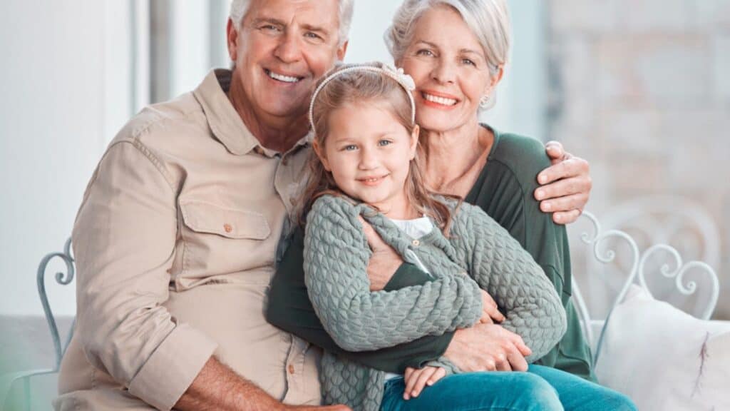 Little girl and her grandparents looking at the camera while sitting together