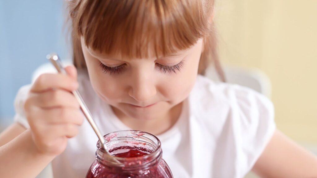 Little girl eating jam