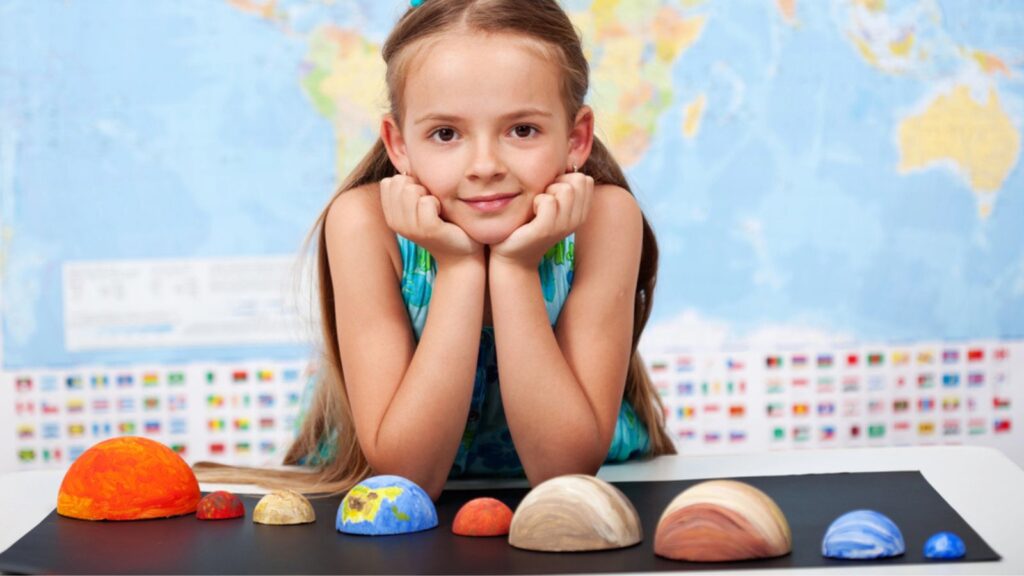 Little girl in elementary science class with her home project