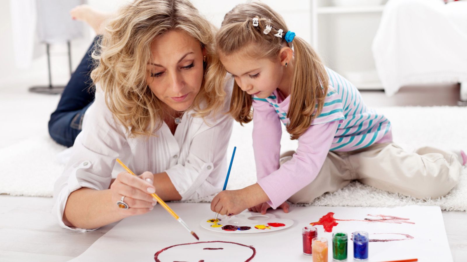 Little girl painting with her mother