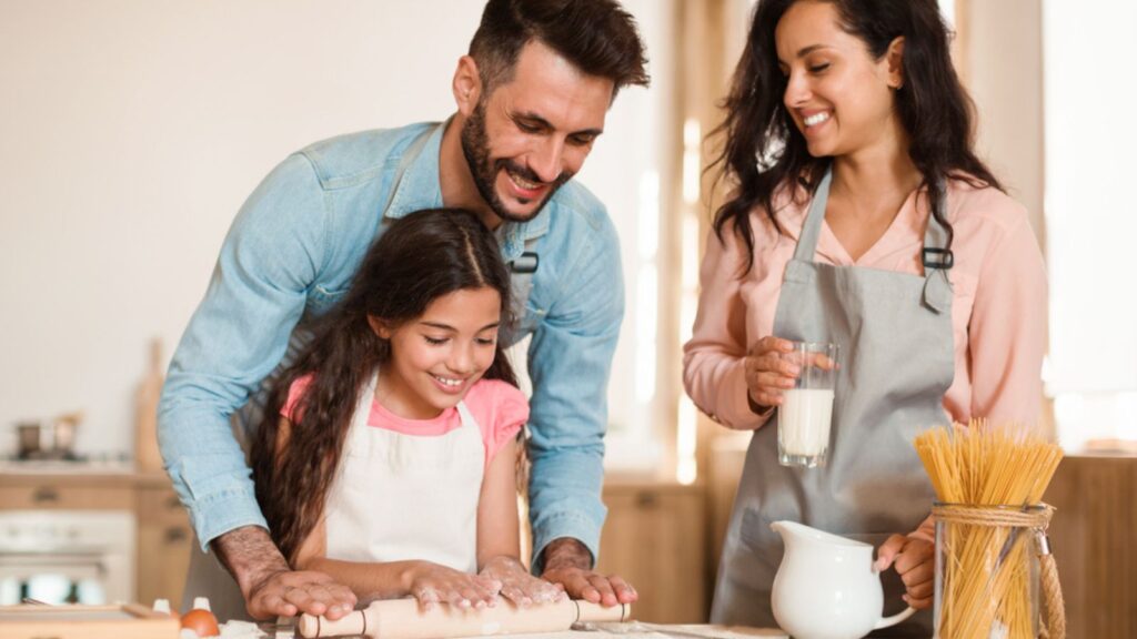 Loving parents teaching their daughter baking pastry