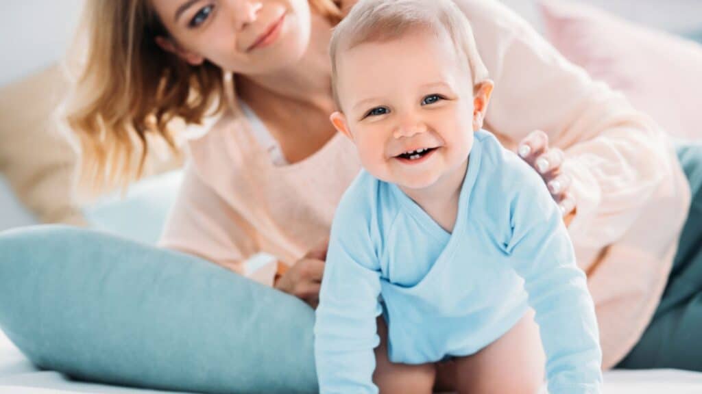 Mother and happy little child looking at camera together while relaxing in bed