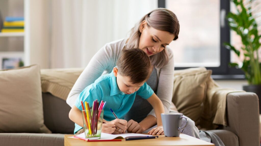 Mother and son writing with workbook at home