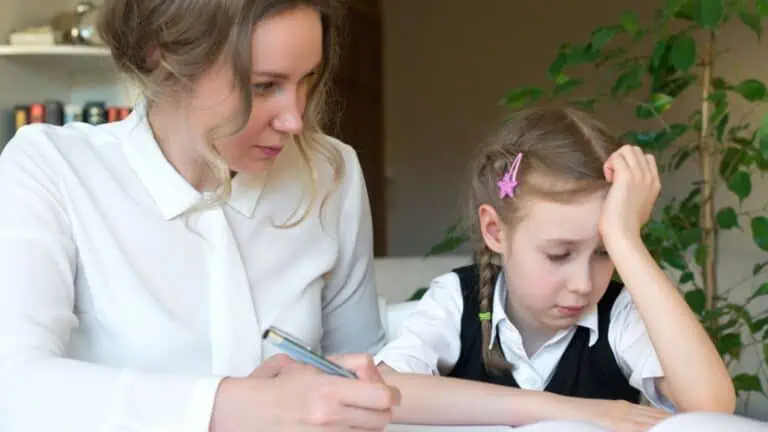 Mother helping her tired daughter with homework at home