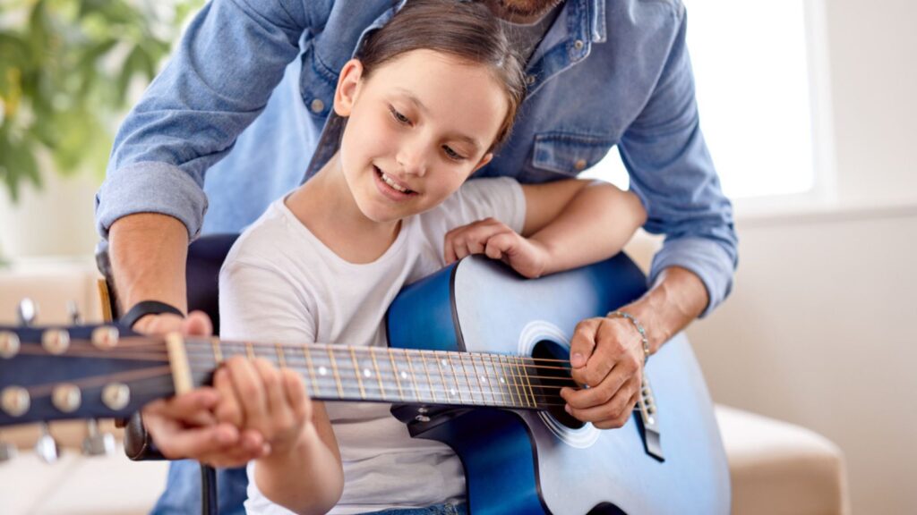 Photo of adorable pretty girl and man hold guitar teaching new chord at home