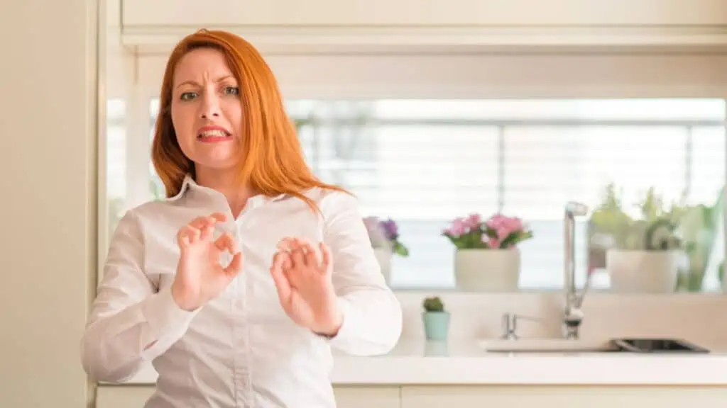 Redhead woman at kitchen disgusted expression