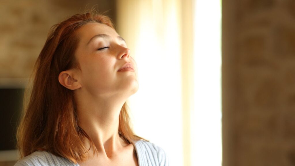 Redhead woman breathing fresh air in the living room at home