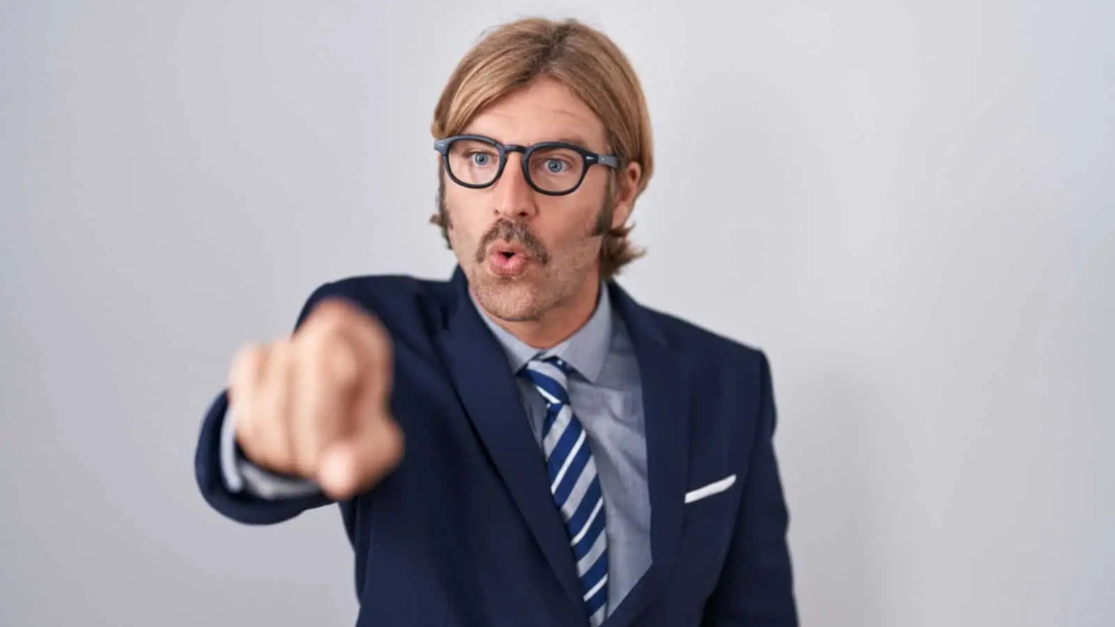 Rude man with mustache wearing business clothes pointing with finger surprised ahead