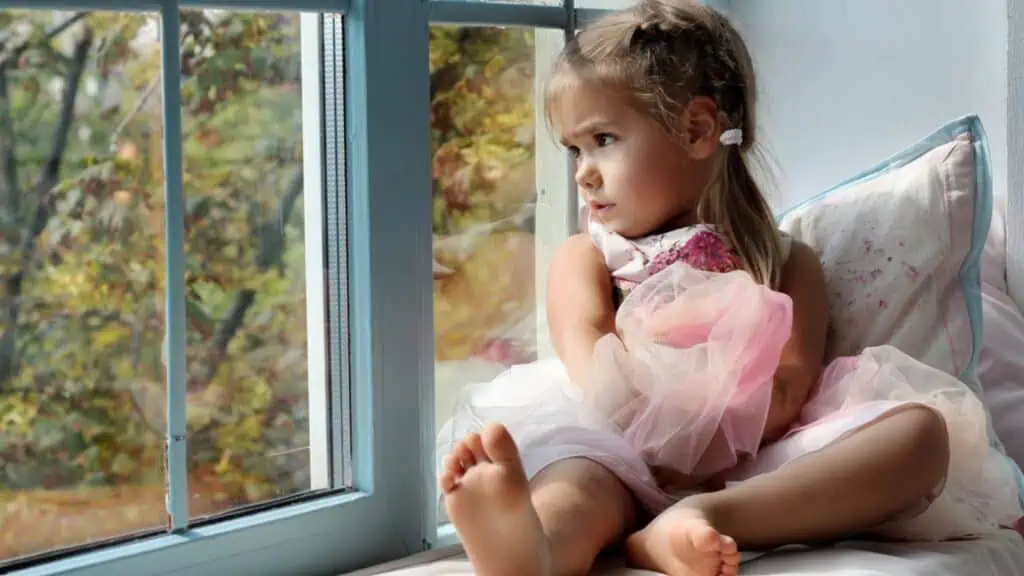 Sad little girl looking at the window