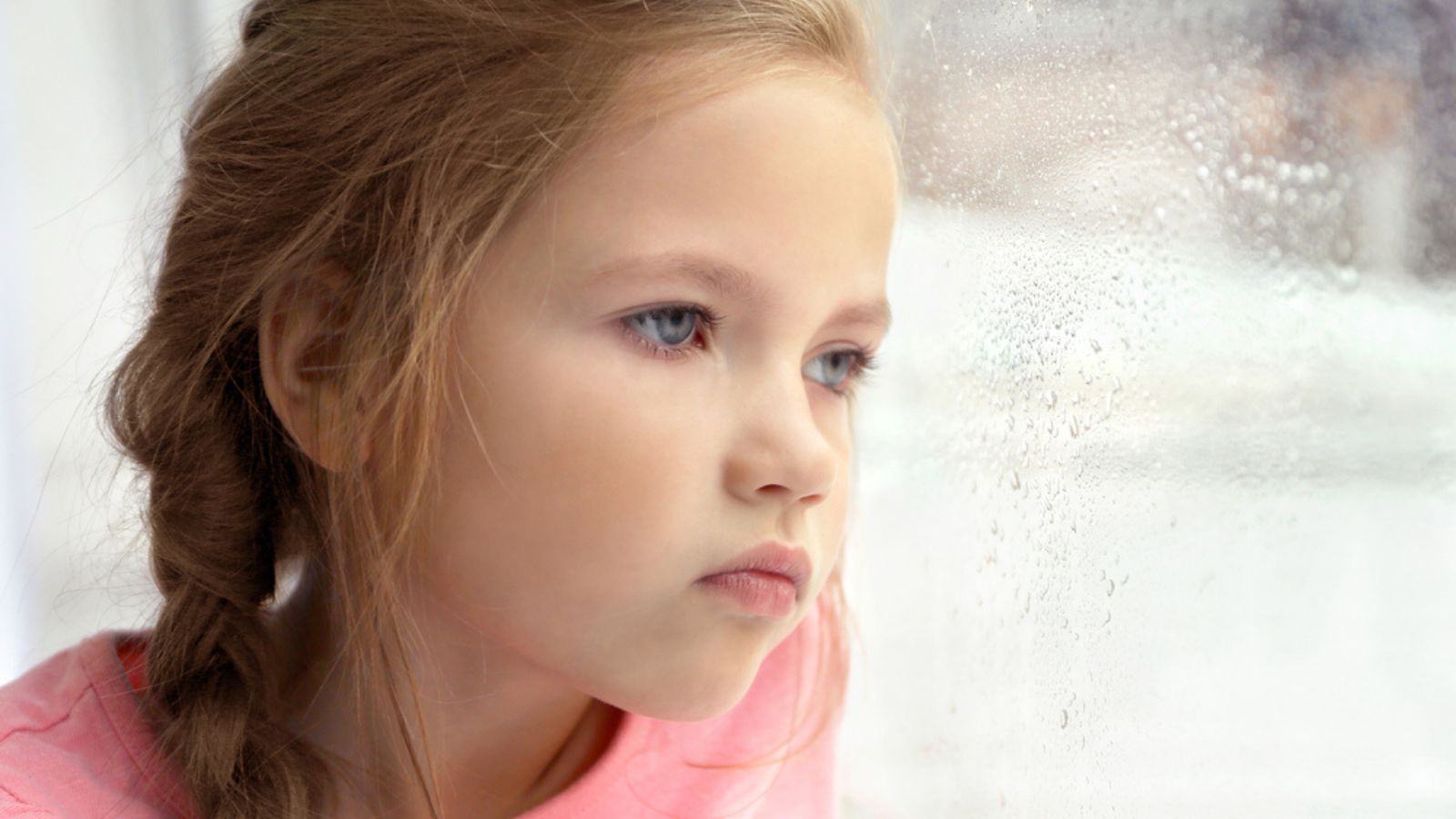 Sad little girl looking out of window