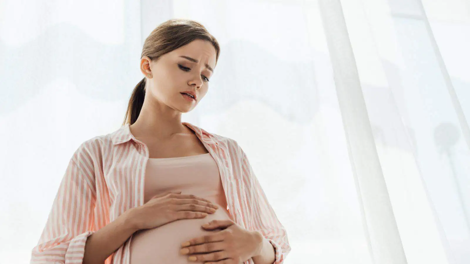 Sad worried pregnant woman touching belly