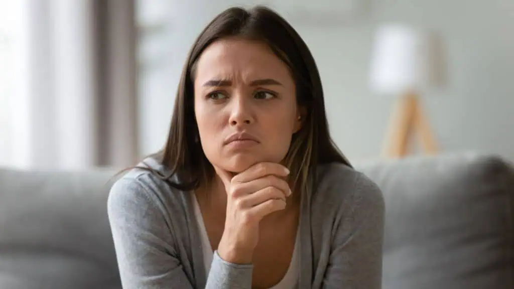 Sad young frowning woman worrying about difficult decision