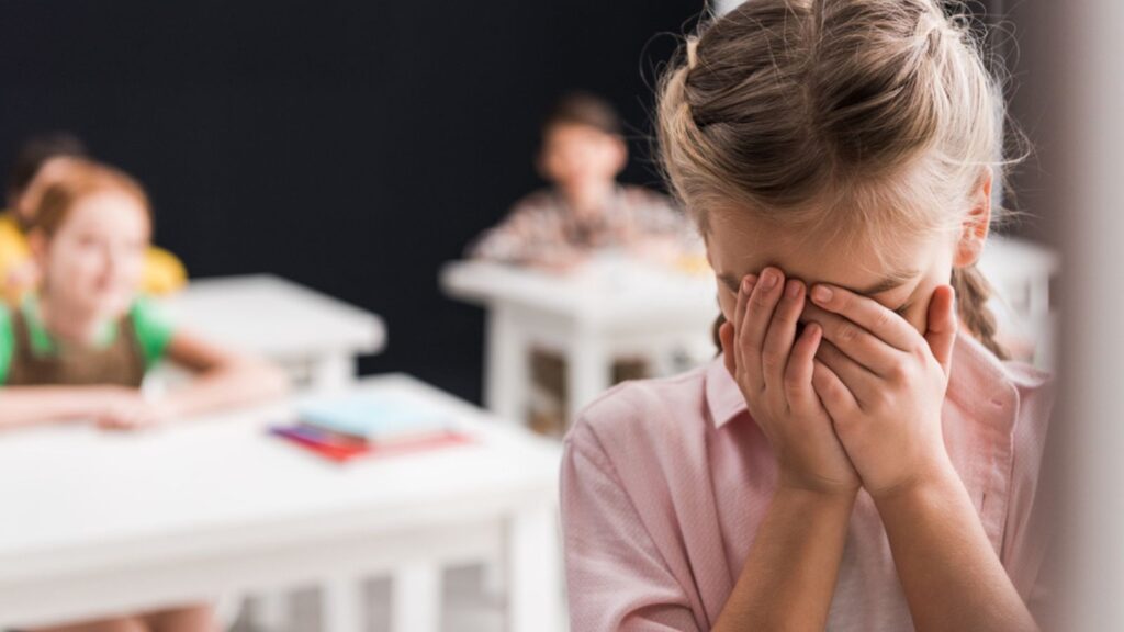 Selective focus of frustrated schoolkid crying near classmates, bullying concept