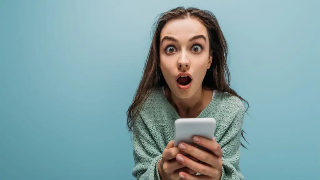 Shocked woman with open mouth using smartphone