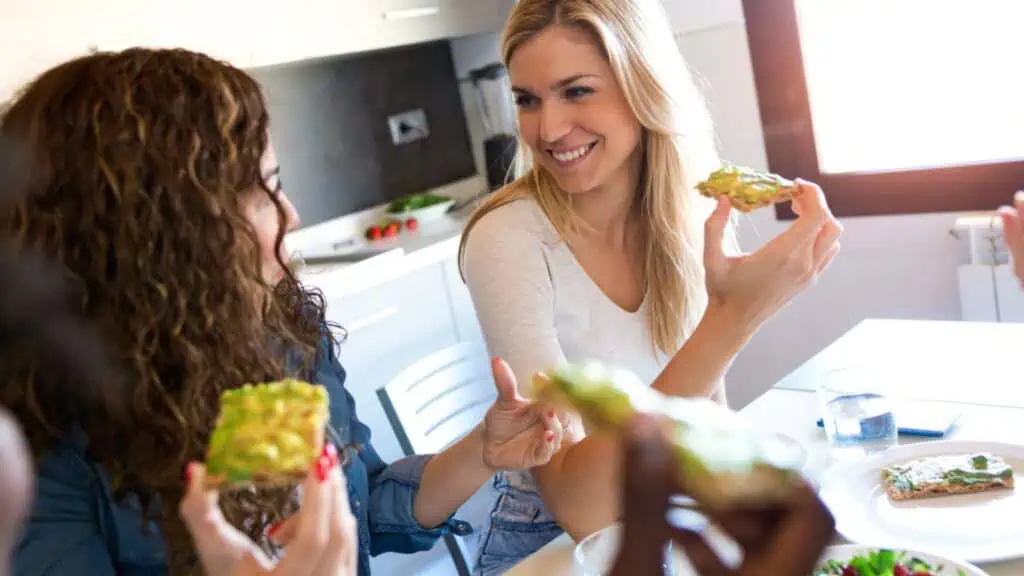 Shot of group of friends laughing while eating healthy food at home