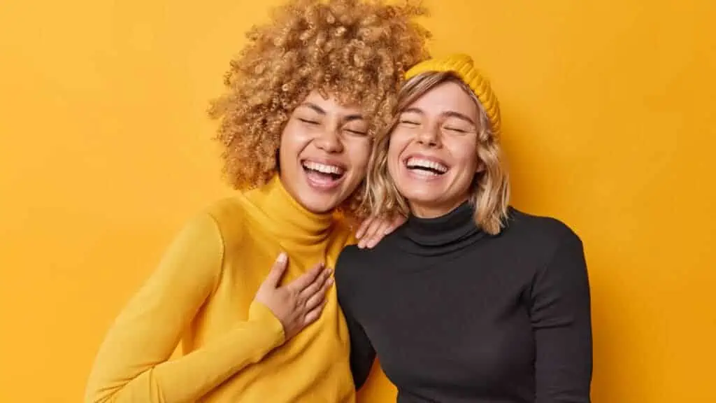 two woman laughing in yellow