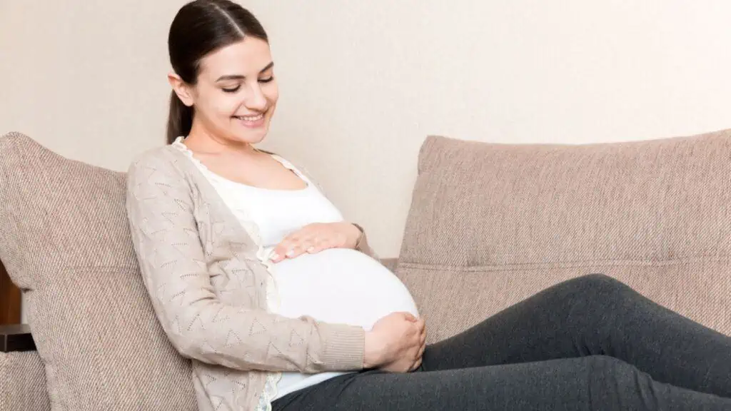 Smiling pregnant woman lying on sofa