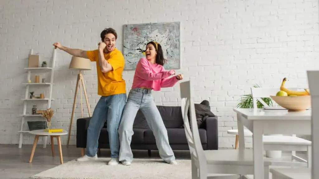 Smiling young couple in casual clothes dancing in modern loft