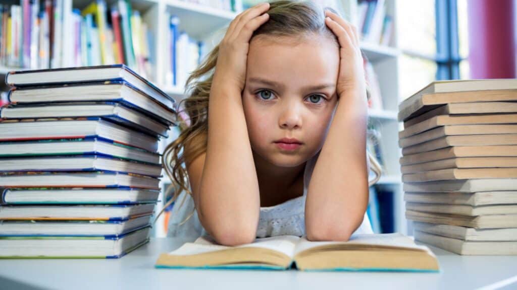 Stressed girl with books at table