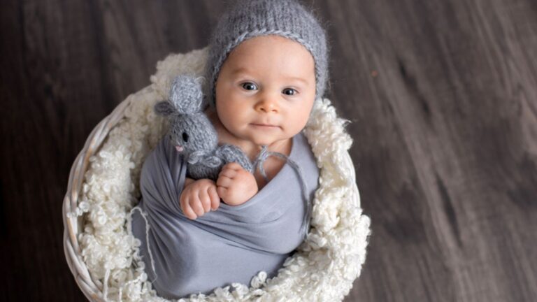 Sweet baby boy in basket, holding and hugging teddy bear