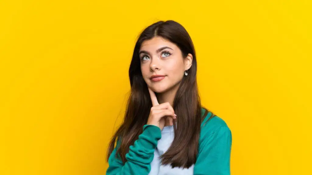 Teenager girl over yellow wall thinking an idea