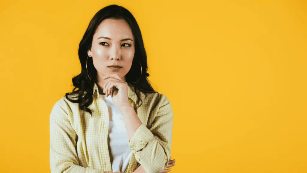 Thinking Asian woman in yellow background