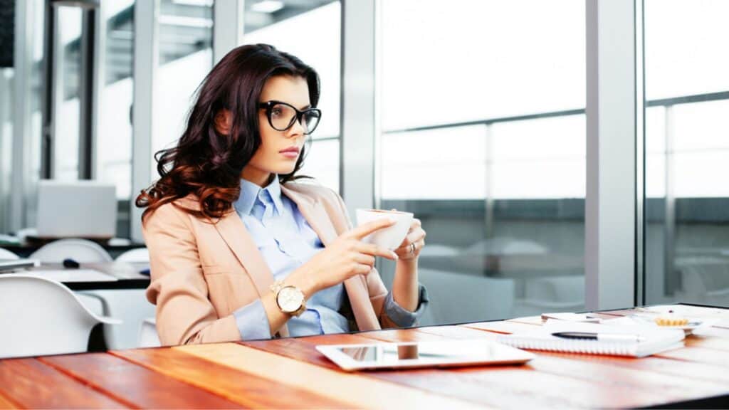 Thinking woman looking in distance and holding coffee