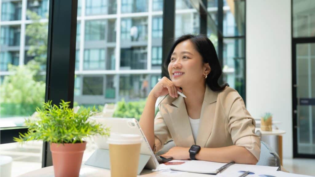 Thinking woman working on laptop at coffee shop