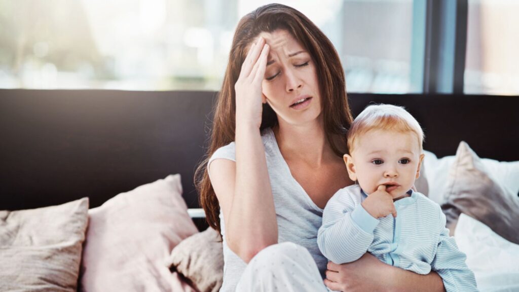 Tired sad depressed mother carrying her child in bed