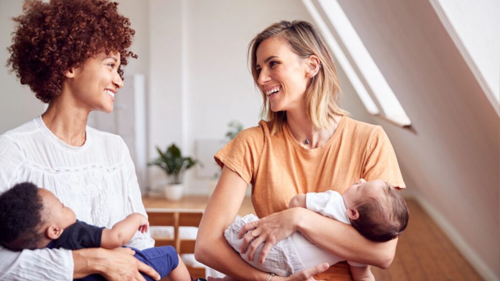 Two Mothers Meeting Holding Newborn Babies At Home