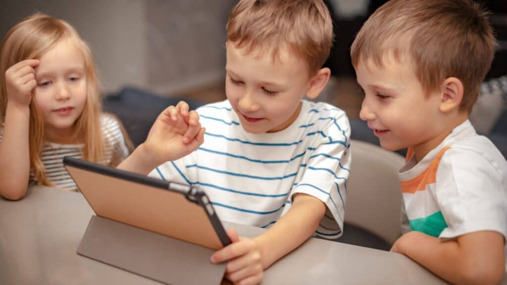 Two boys and a girl play on an tablet at home