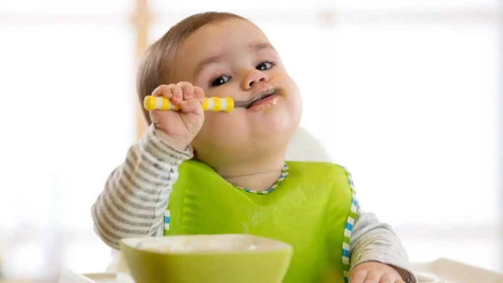 baby eating with a spoon bowl bib