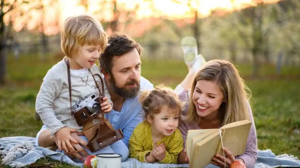 happy family reading on a picnic blanket book