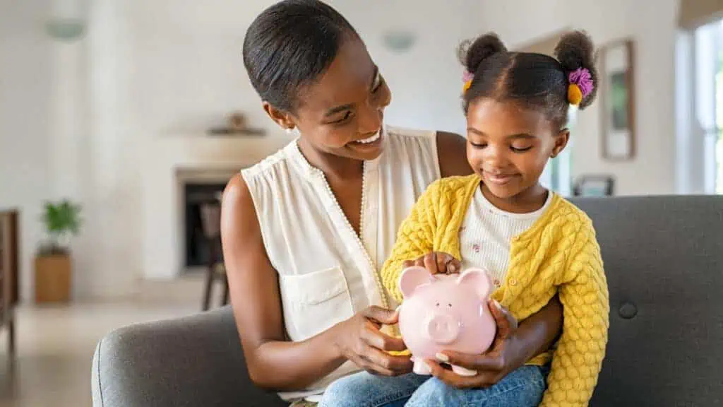 mom and girl holding a piggy bank money saving
