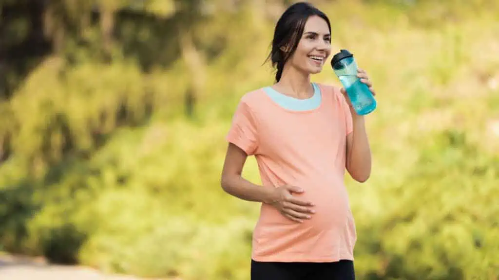 pregnant woman exercising drinking water happy outside