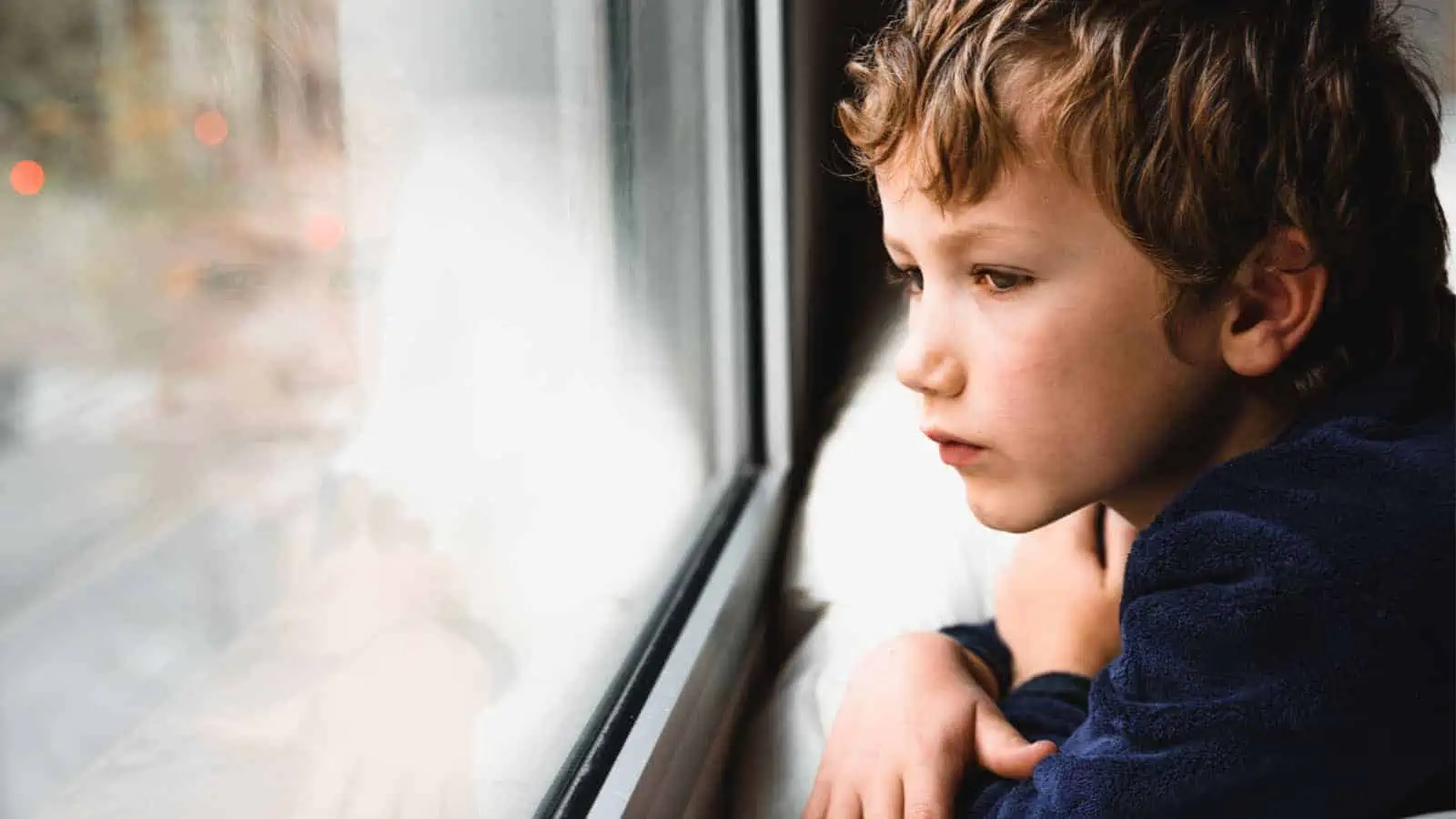 sad boy looking out the window