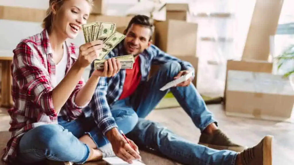 happy couple holding money and paying bills