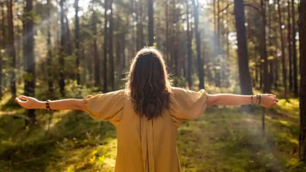 woman outside nature woods empowering arms outstretched