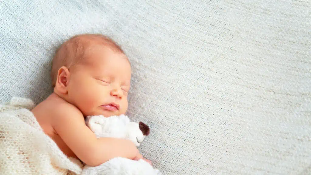 sleeping newborn baby with a teddy bear