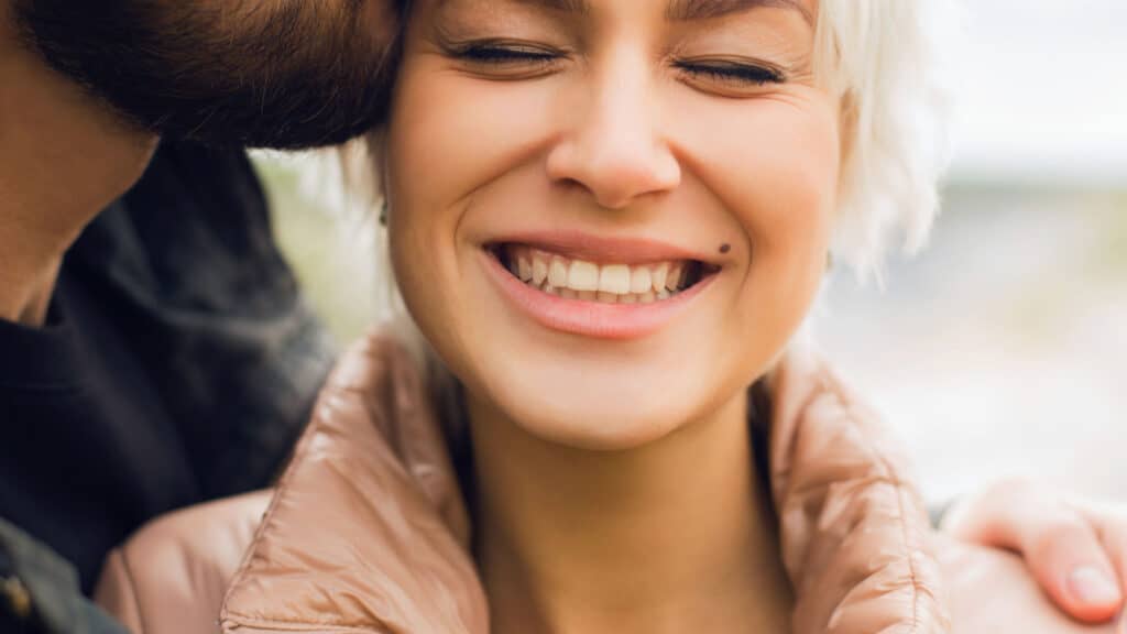 happy woman and couple kiss on the cheek