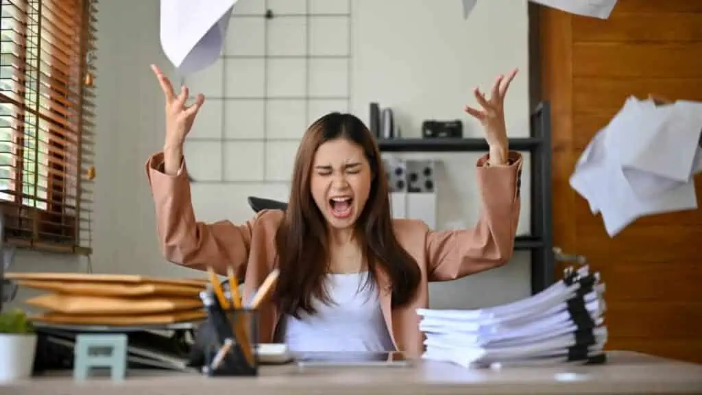 mad woman with paperwork at computer